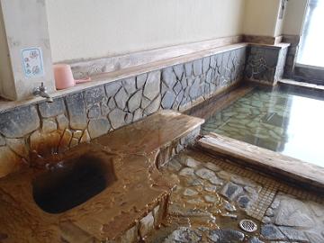 掛け湯の湯壺周りに付着した厚い析出物の層の写真